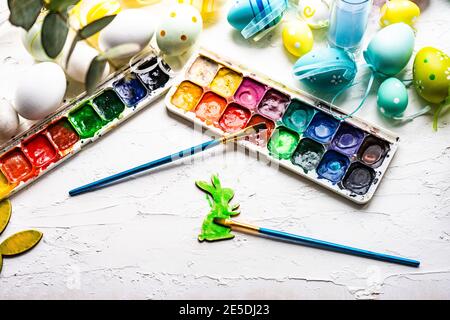 Two paint brushes, a palette with watercolour paints and Easter eggs Stock Photo