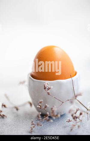 Boiled egg in an egg cup next to dried flowers Stock Photo