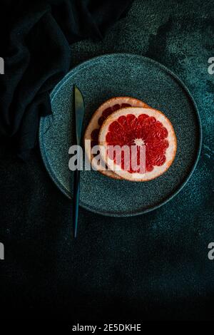 Ripe pink grapefruit slices on black plate Stock Photo