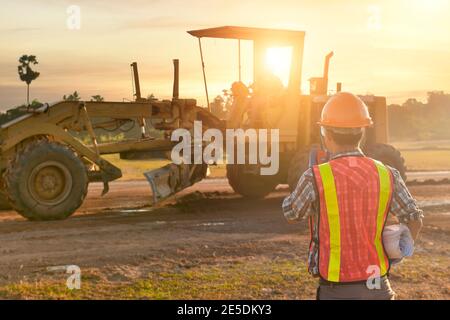 Rear view of an engineer on road construction site talking on a walkie-talkie, Thailand Stock Photo
