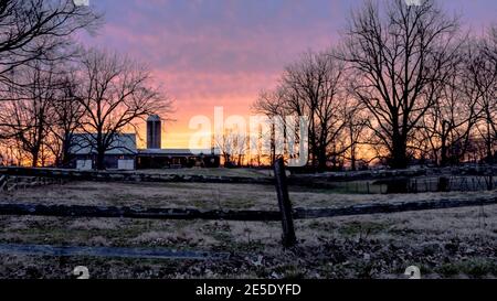 Sunset in rural Kentucky over a dairy farm with split rail fence in the foreground Stock Photo