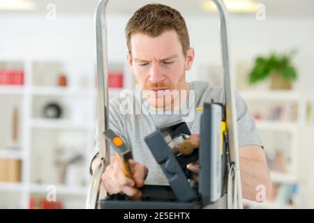 man looking in toolbox on stepladder Stock Photo