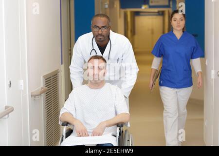 doctor pushing male patient in wheelchair Stock Photo