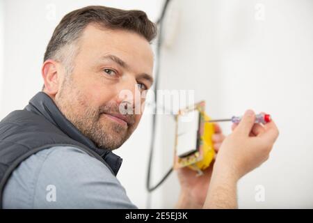 electrician mounting electric sockets on the wall indoors Stock Photo