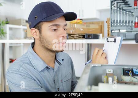 male technician writing on clipboard in kitchen Stock Photo