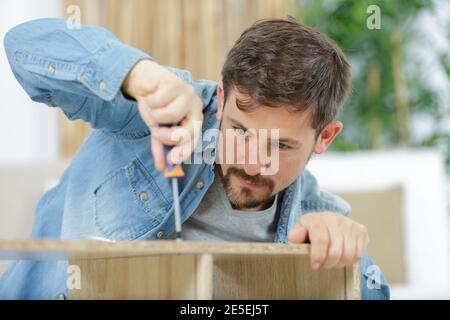 man screws the leg to the bottom of the bed Stock Photo