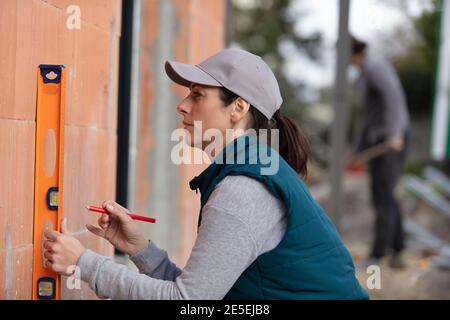 young woman using spirit level on house under construction Stock Photo
