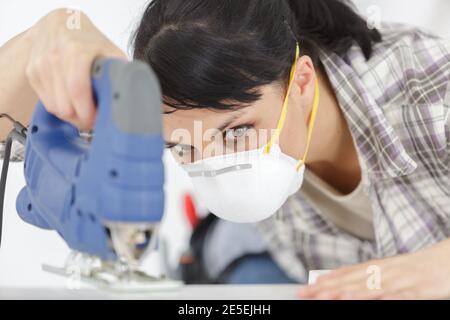 woman joiner in home workshop using a saw cut Stock Photo