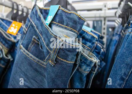 Closeup many jeans hanging on a rack. Row of pants denim jeans hanging in closet. concept of buy , sell , shopping and jeans fashion. Stock Photo