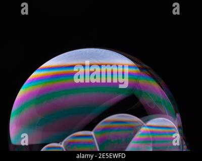 Set of soap bubbles with color gradient isolated on black background. Close-up Macro shot. Stock Photo