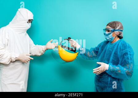 Stock photo of unrecognized person talking with healthcare worker wearing protective suit for covid19. Stock Photo