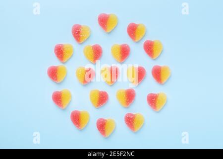 Colorful gummy hearts on blue background. Jelly sweets in circle shaped. Top view - Image Stock Photo