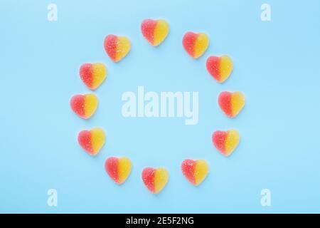Colorful gummy hearts on blue background. Jelly sweets in circle shaped. Top view - Image Stock Photo