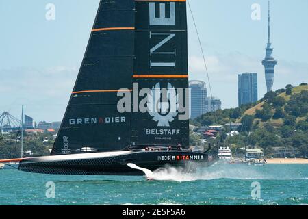 INEOS Team UK's Britannia, skippered by Sir Ben Ainslie, sails in front of the Auckland's North Head and the Sky Tower during the  first round of raci Stock Photo