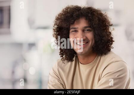 A CURLY HAIRED MAN LAUGHING HAPPILY IN FRONT OF CAMERA Stock Photo