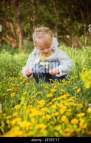 little girl on the dandelions meadow in spring day Stock Photo