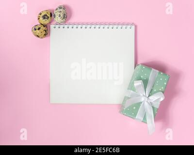 a blank sheet of paper surrounded by quail eggs on a pink background Stock Photo