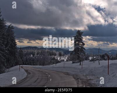 Stunning view of curvy road Schwarzwaldhochstraße in winter surrounded by deep snow and frozen trees near Schliffkopf peak, Germany in Black Forest. Stock Photo