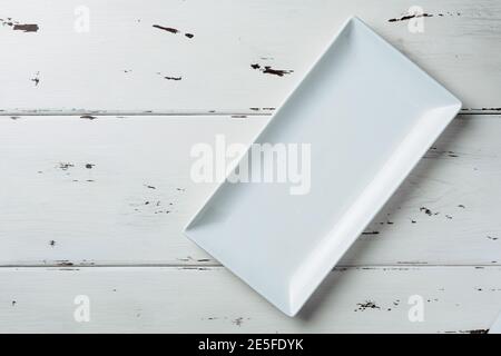 Top view of a white rectangular plate on a white wooden background. Flat lay. Copy space. Stock Photo
