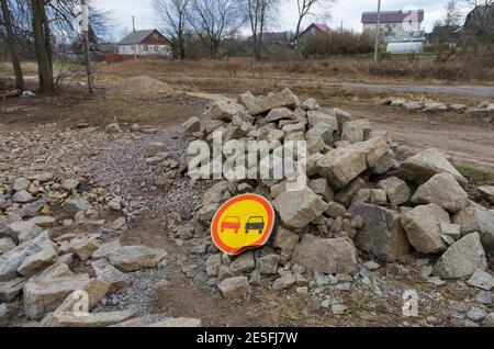 Bent widespread road sign 'No overtaking' on a large pile of rocks Stock Photo