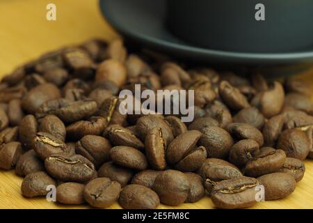 A beautiful background of natural coffee beans and a coffee cup in the background. Stock Photo