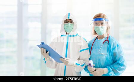 International doctor team. Hospital medical staff in hazmat suit, face shield and mask. Mixed race Asian and Caucasian doctor and nurse meeting. Clini Stock Photo