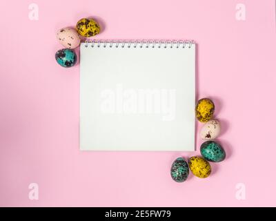a blank sheet of paper surrounded by easter eggs on a pink background Stock Photo