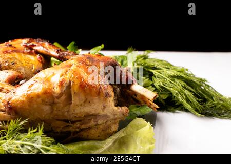 Rabbit meat baked with vegetables and herbs on a plate on a black white background Stock Photo