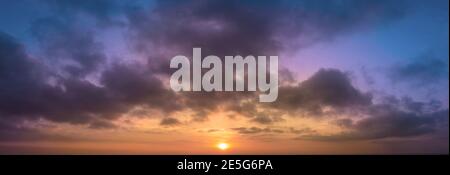 Panoramic abstraction of sunrise with dramatic blurred background of clouds and blue sky. Stock Photo