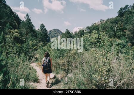 Girl walking along a small path in the mountain of Prades, Tarragona, Spain. On a sunny summer day Stock Photo