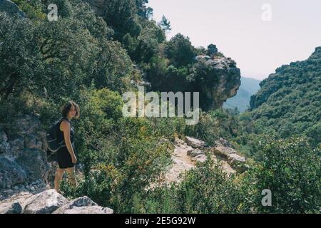 Girl walking along a small path in the mountain of Prades, Tarragona, Spain. On a sunny summer day Stock Photo