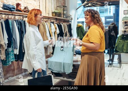 Clothing store owner talking with influencer and showing apparel in stock  to create advertisement. Shopping mall worker chatting with fashion blogger  and displaying garment for promotion 33861713 Stock Photo at Vecteezy