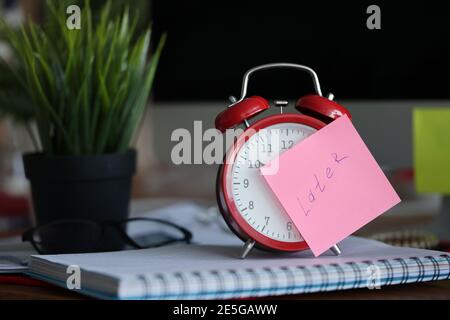 Red alarm clock standing on table near flowerpot in office closeup Stock Photo