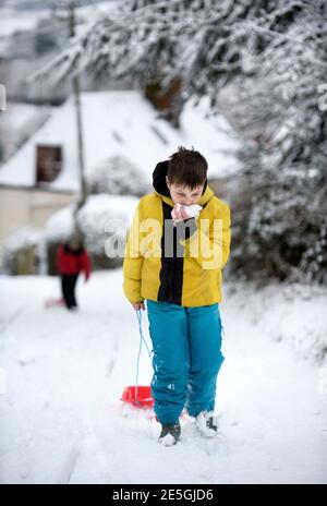 Two boys head out sledging in Wotton-under-Edge, Gloucestershire UK Stock Photo