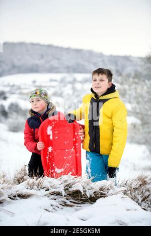 Two boys head out sledging near Wotton-under-Edge, Gloucestershire UK Stock Photo