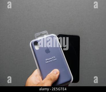 Paris, France- Sep 26, 2018: POV male hand holding new Apple Silicon Case and the latest iPhone smartphone telephone - isolated on gray background Stock Photo