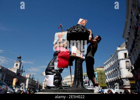 A demonstrator puts up banners on the main statue of a bear in Madrid's Puerta del Sol May 22, 2011. Tens of thousands of protesters have daily joined those camped out for the past week to protest against government austerity before regional elections on Sunday which are likely to deal a blow to the Socialist government. An estimated 30,000 were on Madrid's Puerta del Sol plaza on Saturday night, demonstrating against the government's handling of an economic crisis which broke out in 2008. REUTERS/Paul Hanna  (SPAIN - Tags: POLITICS CIVIL UNREST ELECTIONS)