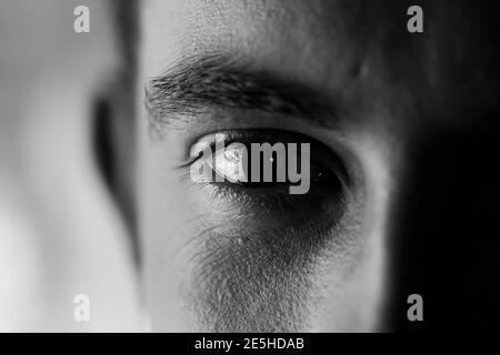 Expressive strong look - closeup of an eye looking sad and empty, high contrast black and white shot Stock Photo