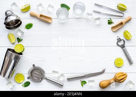 Frame of bar equipment and cocktail ingredietns - shaker, lime and ice. Overhead view Stock Photo