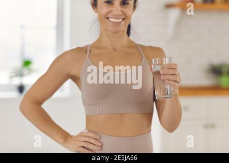 Happy woman holding glass of fresh water and recommending drinking enough liquid daily Stock Photo