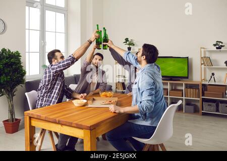 Group of young friends drinking beer, eating pizza and having good time together Stock Photo