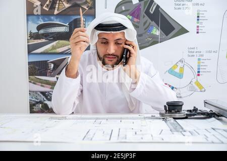 Arab male architect speaking on the phone while working Stock Photo