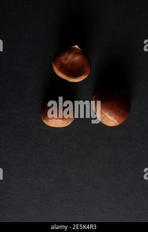 Edible sweet whole chestnuts pattern on black background with copy space. Stock Photo