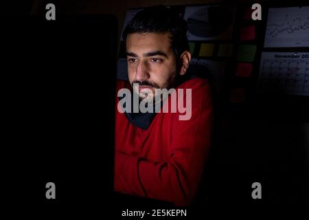 Young man feeling cold in the dark in front of his laptop while working Stock Photo