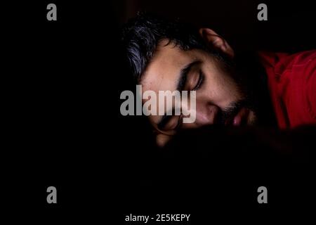 Young man is sleeping in his dark office after long term of working and overtime in front of his laptop Stock Photo
