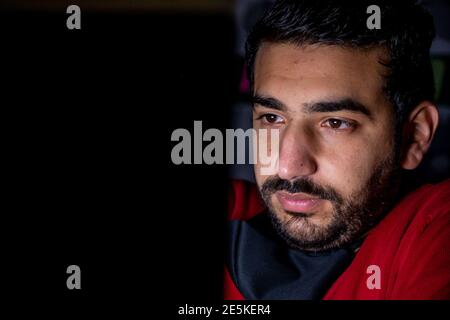 Young man in the overtime in the dark from his office working hard on his project with a serious look on his face Stock Photo