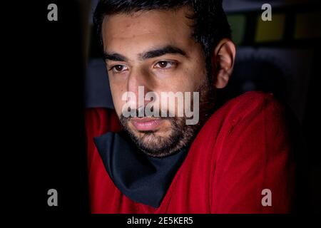 Young man feeling cold in the dark in front of his laptop while working Stock Photo