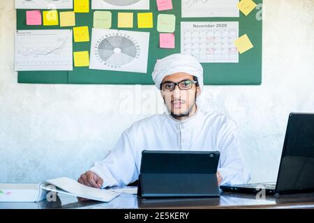 Young arabian man is making a live video from his office in front of his laptop Stock Photo