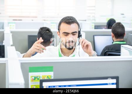 Young man working at a computer in a call centre ,with his colleagues Stock Photo