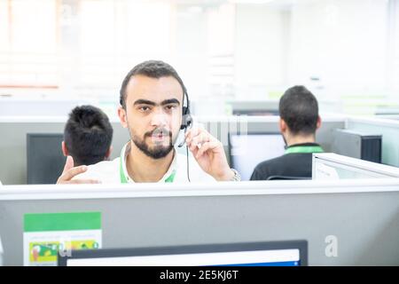 Young man working at a computer in a call centre ,with his colleagues Stock Photo